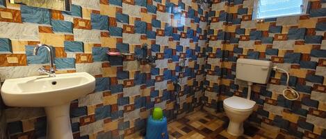 Ein Badezimmer mit gemusterten Fliesen, einem Waschbecken, einer Toilette und einer Duschkabine.