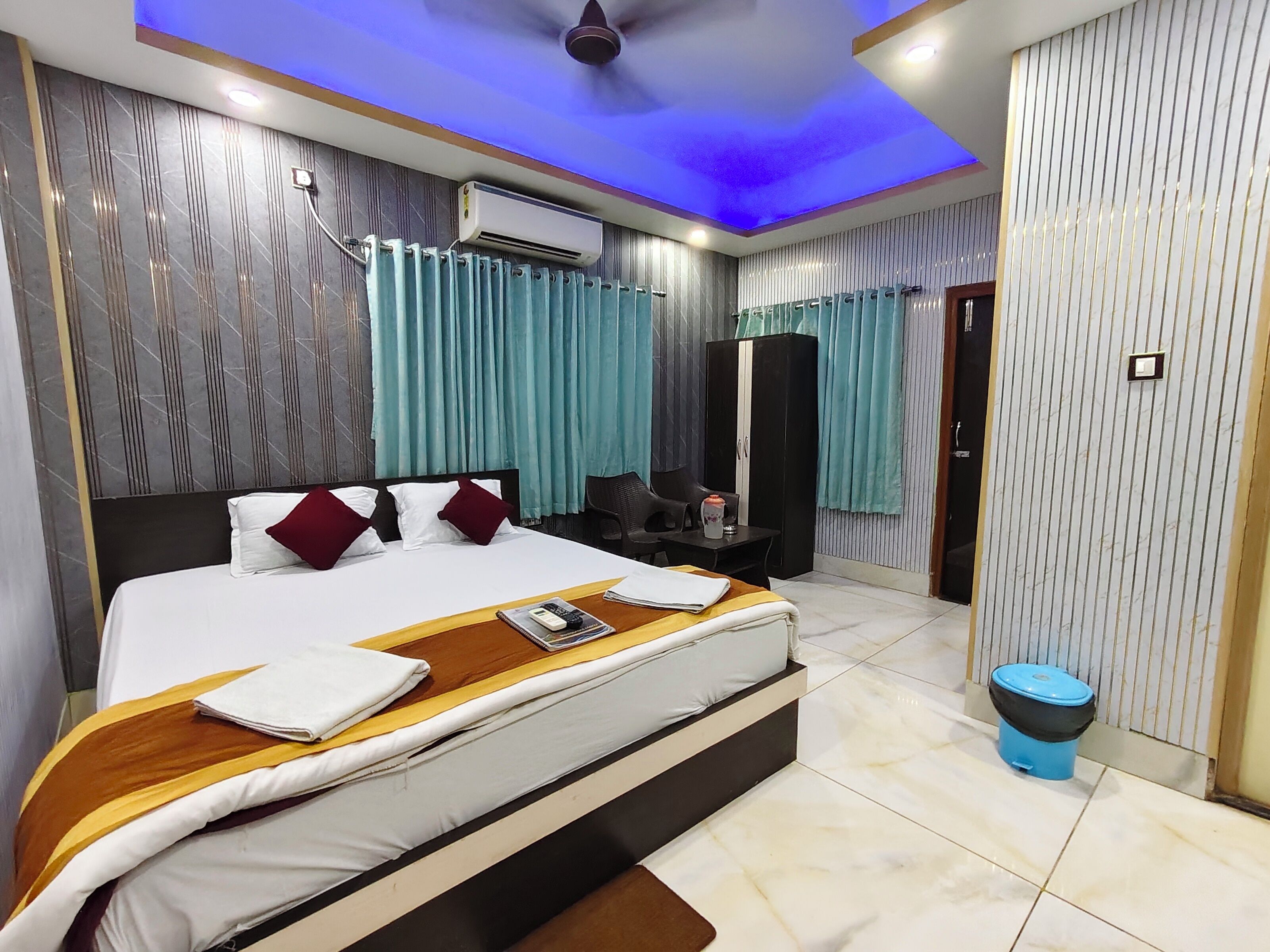 A modern hotel room with a large bed, a desk, a wardrobe, and a ceiling fan.