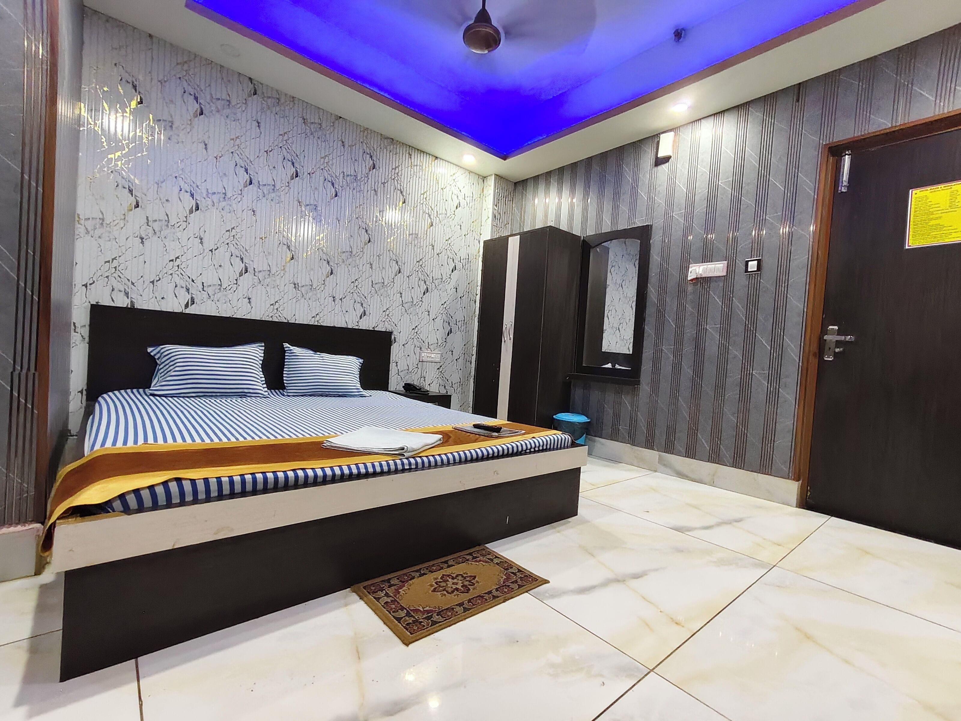 A bedroom with a bed, a nightstand, a mirror, and a door.