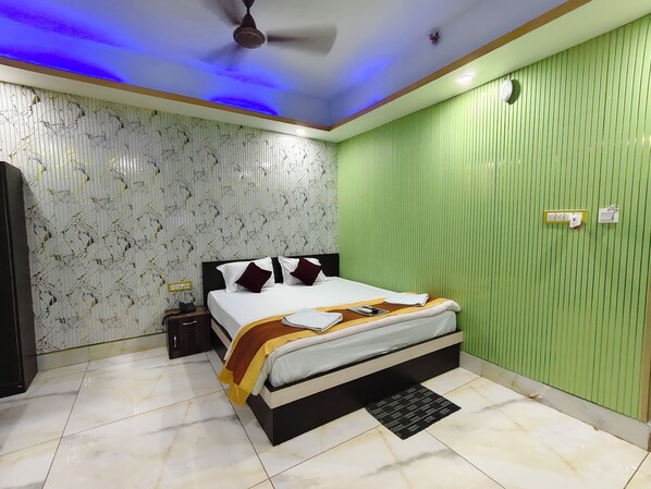 Un dormitorio con cama, ventilador de techo, mesita de noche y pared verde.