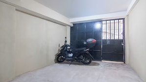 Una motocicleta estacionada en un espacio reducido y cerrado, con un portón negro y suelo de concreto.