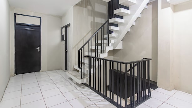 Una escalera con barandilla negra y peldaños blancos, que conduce a un piso superior.