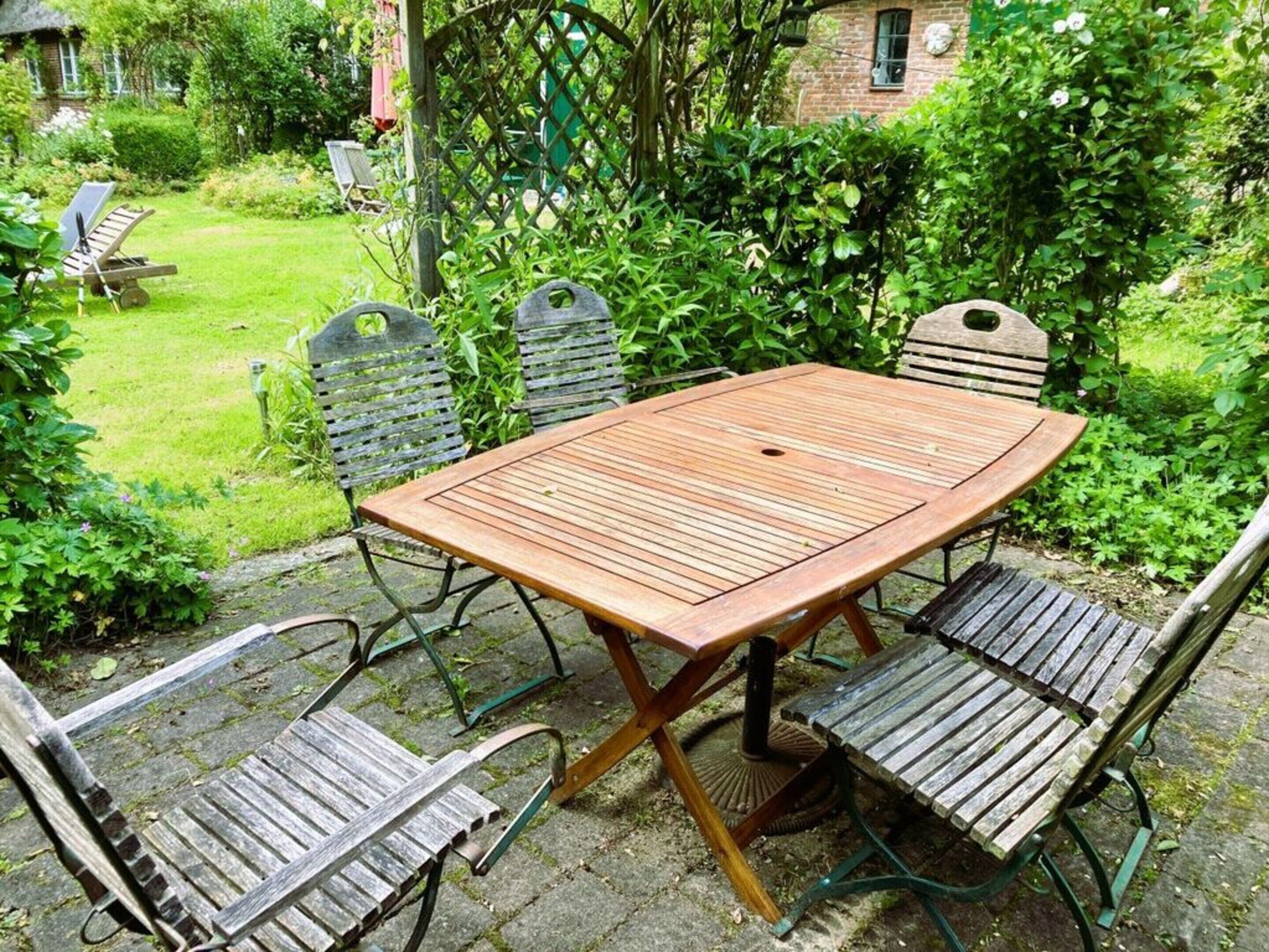 An outdoor patio with a wooden table and four metal chairs.