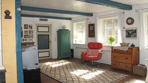 A cozy living room with a red armchair, a green cabinet, and a white radiator. - Romantic Thatched Roof House (Schnarup-Thumby)