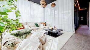 A modern living room with a sofa, a coffee table, and a large window with sheer curtains. - Maison Heurelijk Modern Finished Near Somme-leuze (Somme-Leuze)