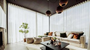 A modern living room with a sofa, coffee table, and a potted plant. - Maison Heurelijk Modern Finished Near Somme-leuze (Somme-Leuze)