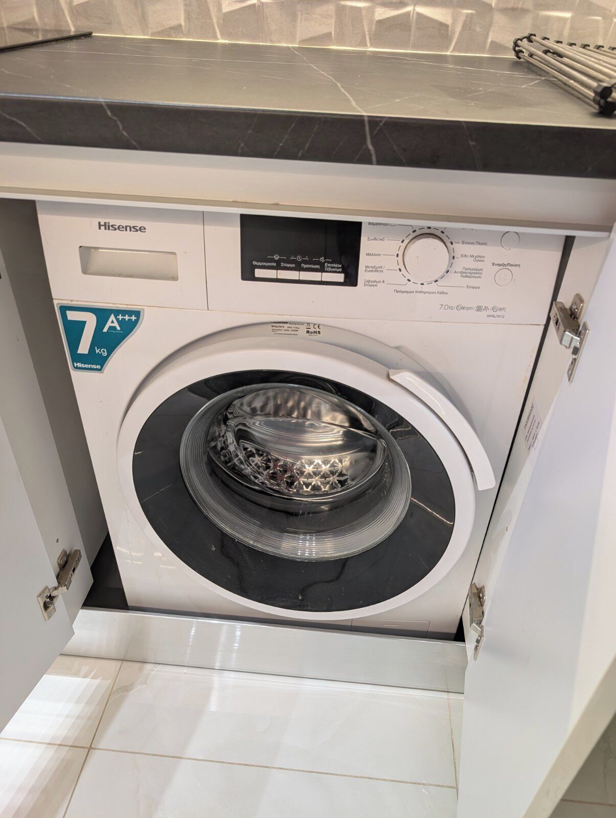 A front view of a Hisense washing machine with a control panel, a 7 kg capacity label, and a circular drum.