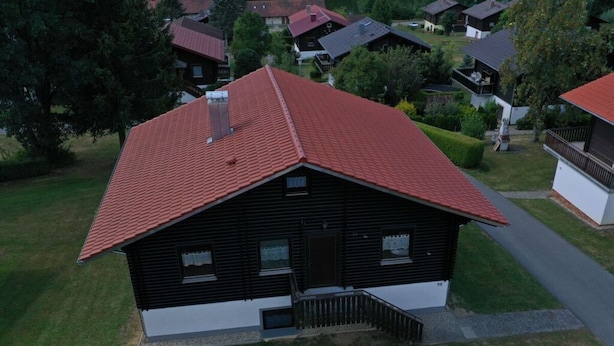 A two-story house with a red roof, a front porch, and a small front yard. - Holiday Apartment Brandl Haus 92 (Arrach)