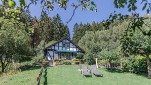 A traditional half-timbered house with a green awning, surrounded by a well-maintained lawn and trees. - Felsberg Modern Retreat (Eslohe)