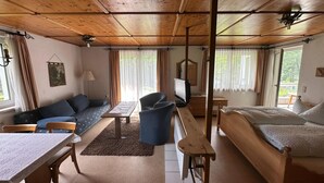 A cozy room with a wooden ceiling, a sofa, a bed, a desk, and a television. - Beautiful Apartment in Gortipohl With Garden (Sankt Gallenkirch)