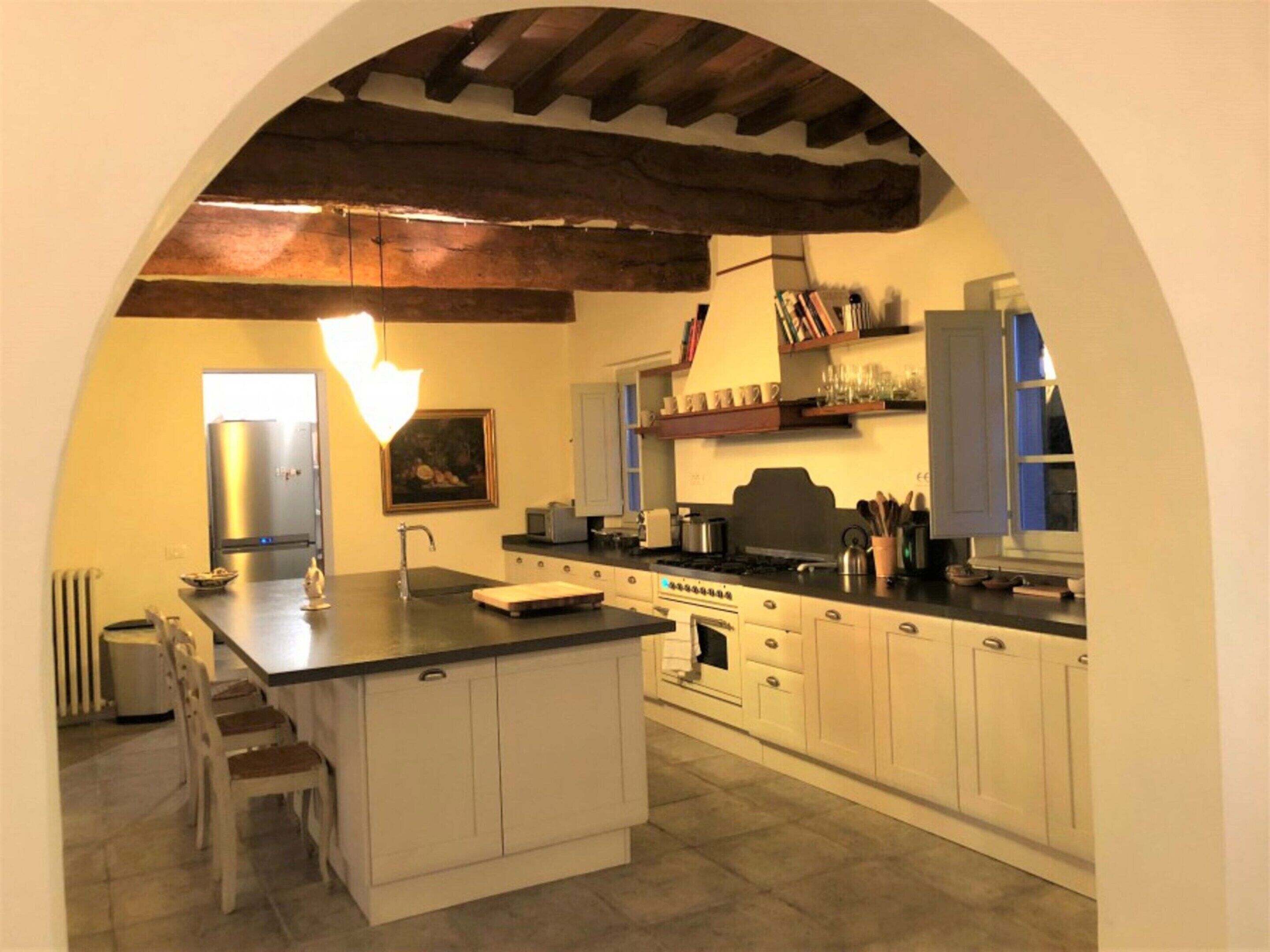 A kitchen with an island, white cabinets, and a wooden ceiling.