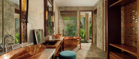 A bathroom with a large copper sink, wooden vanity, and a bathtub.
