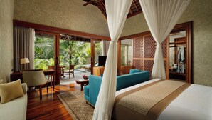 A spacious bedroom with a large bed, a sofa, and a television. There is a balcony with a view of palm trees. - Abisena Wellness & Resort Ubud-Adult Only (Tegallalang)