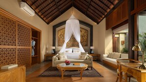 A spacious room with a bed under a canopy, a sofa, a coffee table, and a desk with a lamp. - Abisena Wellness & Resort Ubud-Adult Only (Tegallalang)