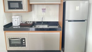 A compact kitchen with a microwave, coffee maker, sink, and a refrigerator. - Desfrute de Momentos Inesquecíveis em Caldas Novas! Casa Aconchegante 3 Suites (Portal das Águas Quentes Caldas Novas)