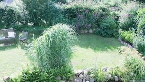 A garden with a pond, surrounded by various plants and a wooden bench.
