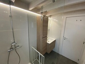 Une salle de bain moderne avec une douche à parois de verre, un meuble-lavabo en bois et un lavabo blanc.