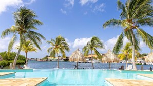 A pool area with palm trees and a view of the sea. - Spanish Water Apartments - Terrace (Jan Thiel)