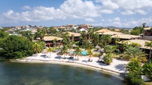 A resort with a pool, palm trees, and beach. - Spanish Water Apartments - Terrace (Jan Thiel)