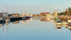 Un port de plaisance où sont amarrés différents types de bateaux, avec une eau calme et des bâtiments en arrière-plan.