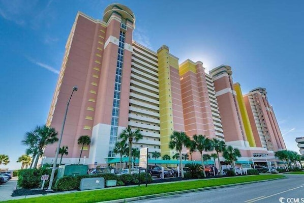 Un hotel de varios pisos con un diseño moderno, que presenta un llamativo diseño a rayas verticales y una estructura cilíndrica central.