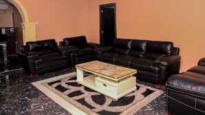 Un salon avec des canapés en cuir noir, un sol en marbre et un tapis à motifs.