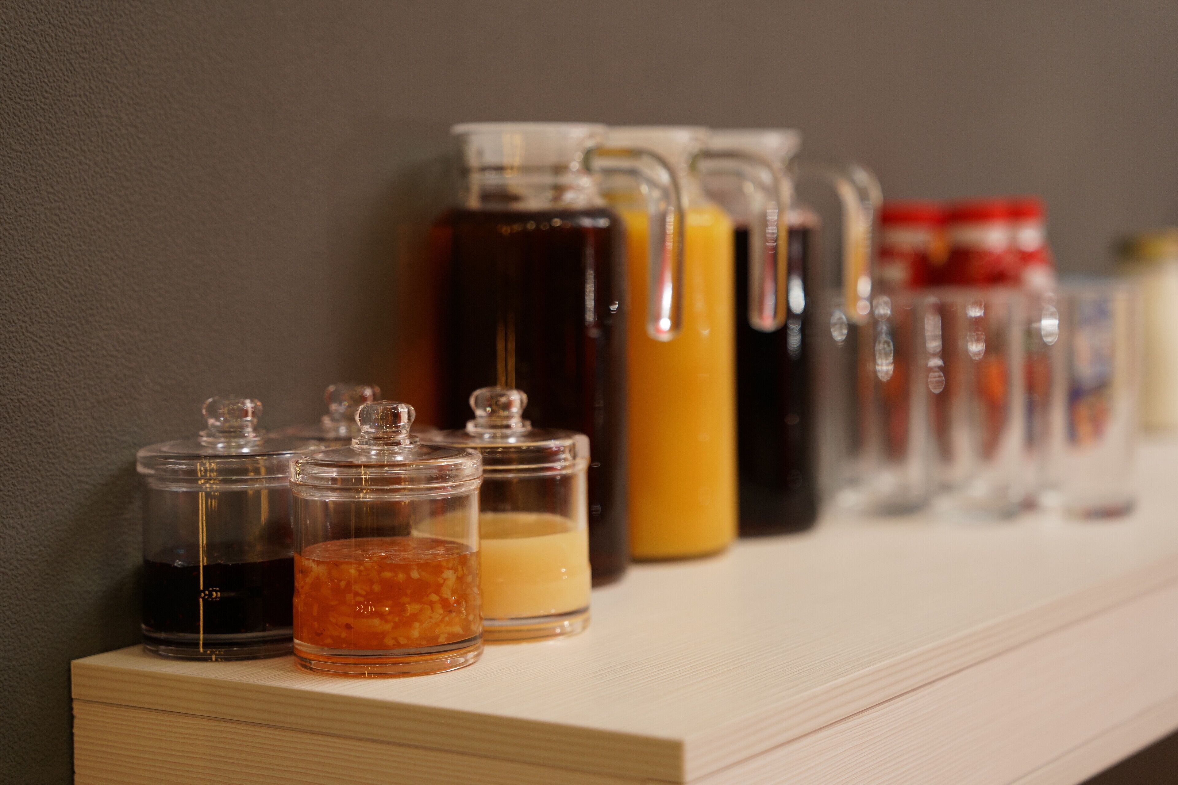 A shelf with various glass containers holding different liquids.