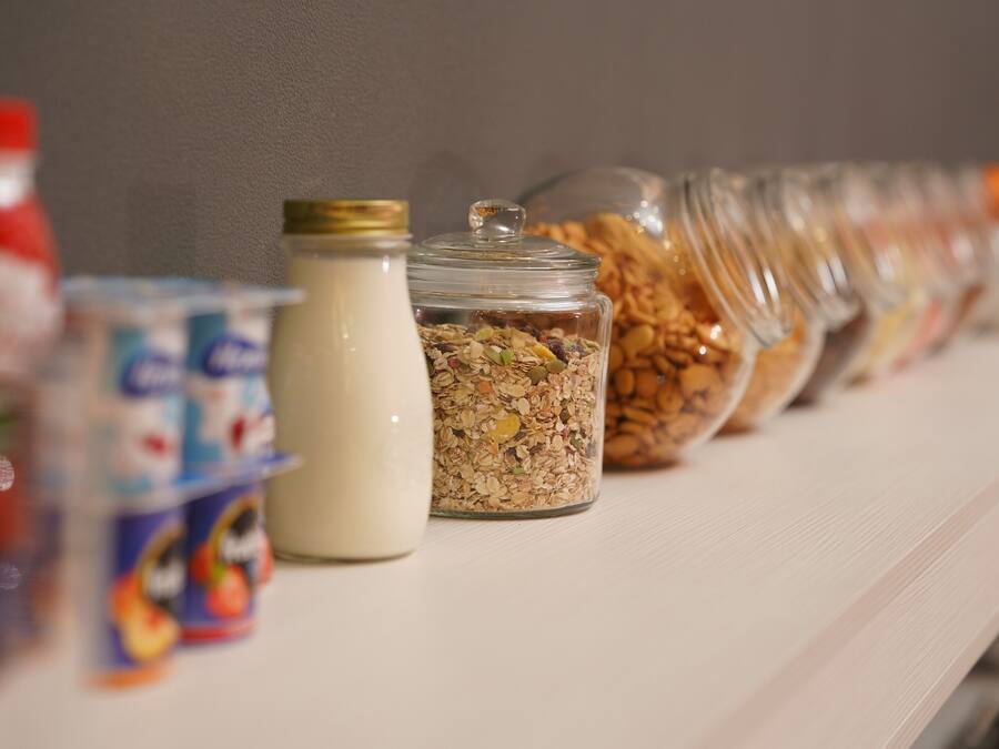 Una hilera de recipientes de comida sobre una estantería.
