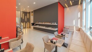 A modern hotel lobby with a reception desk, seating area, and a food display.