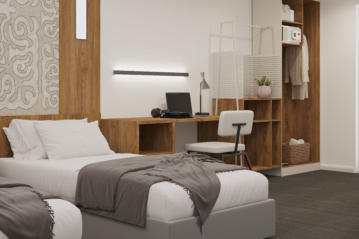 A modern bedroom with a bed, desk, chair, and built-in wardrobe.