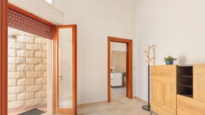A hallway with a wooden wardrobe, a stone wall, and a door leading to a bathroom. - 3900 Leccelsa Dimora by Barbarhouse (Lecce)