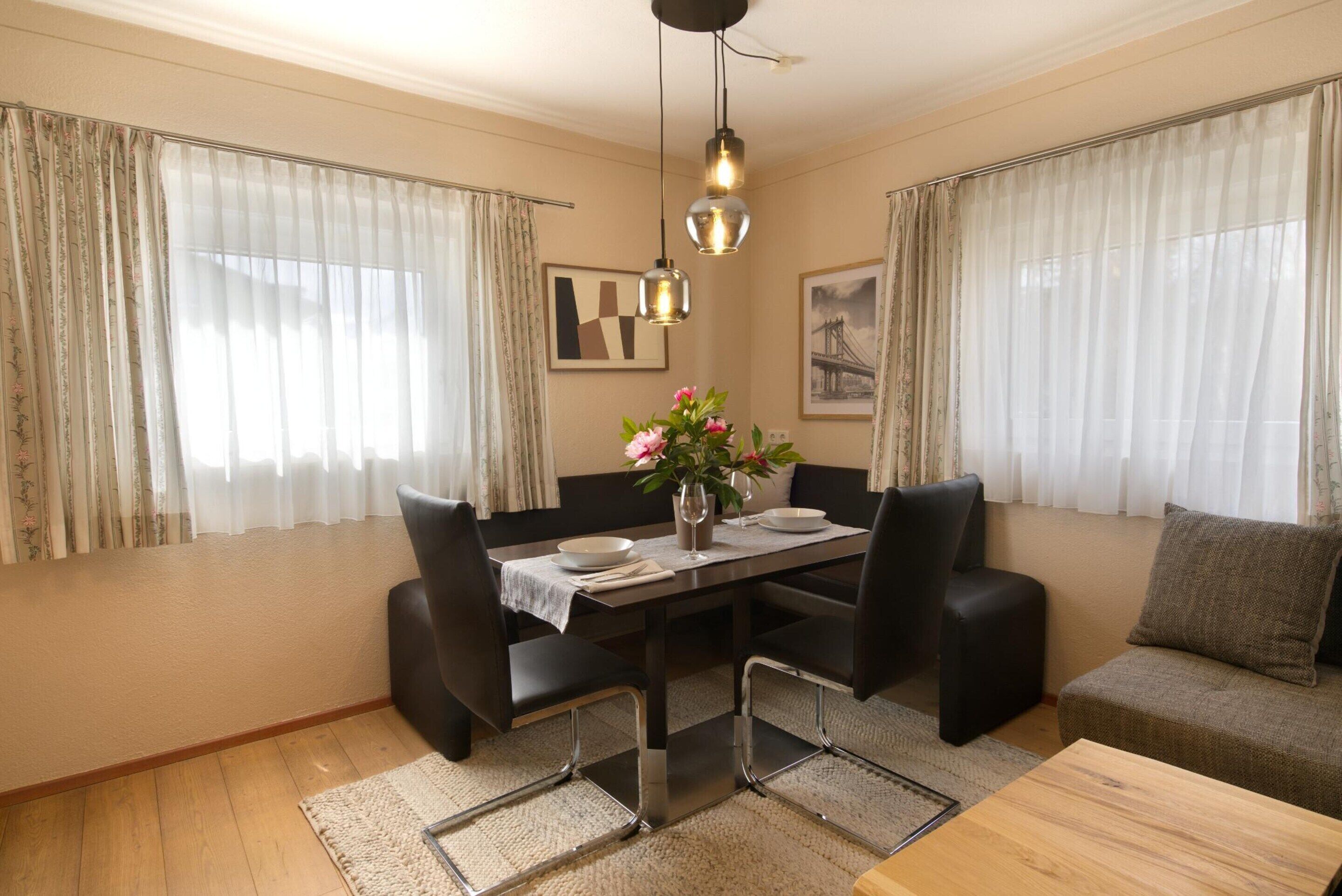 A dining area with a table, chairs, and a vase of flowers.
