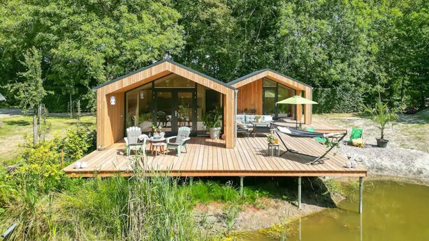 A wooden cabin with a deck, outdoor seating, and a small pool. - Nice Holiday Home in Kortgene With Garden (Kortgene)