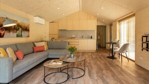 A modern living room with a grey sectional sofa, two round coffee tables, and a large painting on the wall. - Nice Holiday Home in Kortgene With Garden (Kortgene)