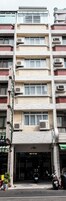 Un edificio de varios pisos con unidades de aire acondicionado, un local comercial con un letrero y una motocicleta estacionada afuera.