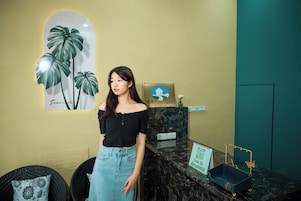 Una habitación con encimera de mármol, un cuadro enmarcado de una casa y una planta pequeña en la pared.