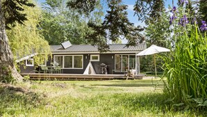 Una baita con una veranda, una zona salotto coperta e una tenda.