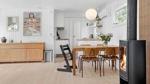 Una cucina moderna con isola centrale, zona pranzo con sedie in legno, piano cottura nero e lampadario a sospensione.