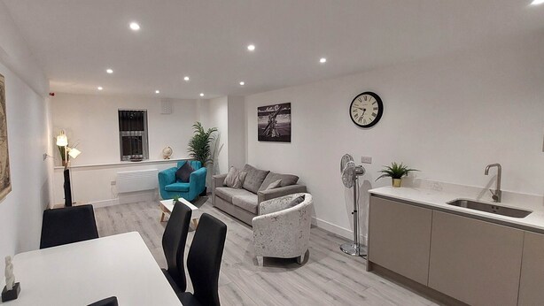 A modern living room with a dining area, a kitchen, and a large window.