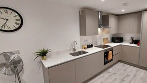 A modern kitchen with a built-in microwave, oven, and stainless steel sink.