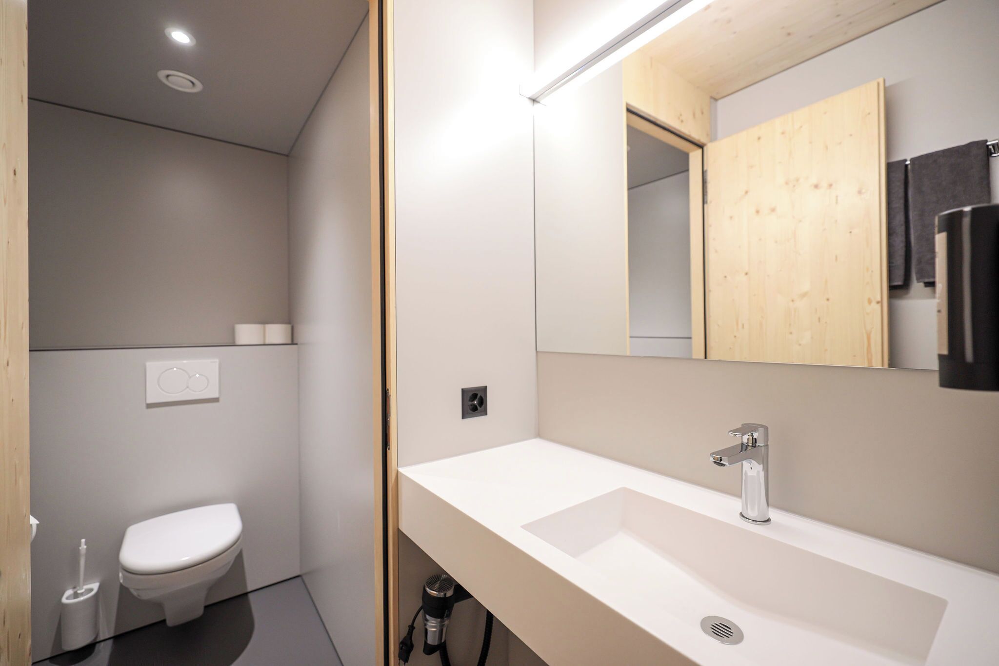 Un baño moderno con un lavabo blanco, un inodoro y un espejo.