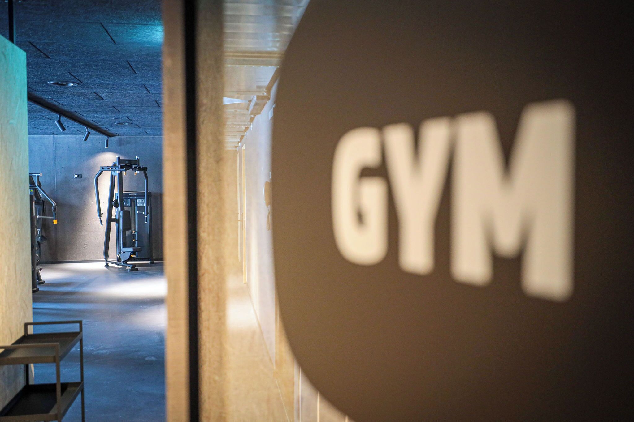 L’intérieur d’une salle de sport, avec des appareils d’exercice et une enseigne sur laquelle on peut lire « SALLE DE SPORT ».