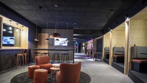 A modern lounge area with seating, a bar, and a television screen. - Revier Mountain Lodge Saas-Fee (Saas-Fee)