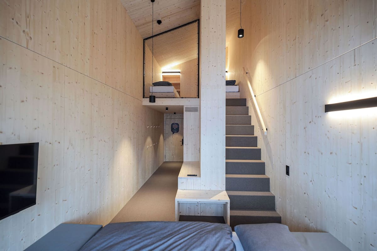 Een modern interieur met houten details, een trap, een bed en een televisie.