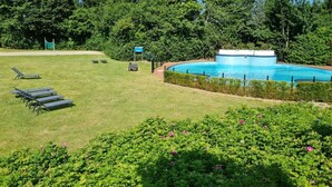 A swimming pool surrounded by a well-maintained lawn with lounge chairs and a small pavilion. - 55 by the Water (Olburgen)