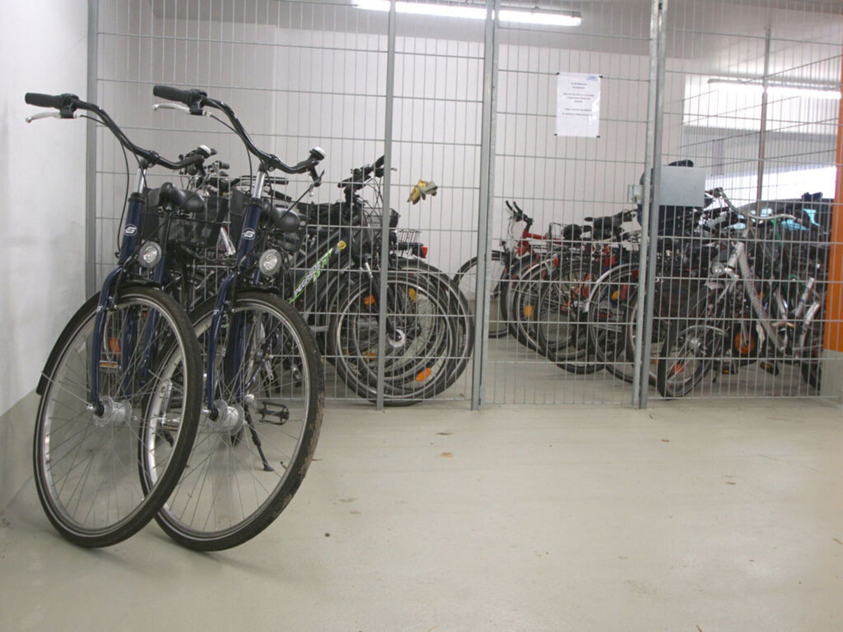 A bicycle storage area with multiple bikes secured in metal cages.