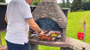 A person grilling meat on an outdoor stone oven. - "sporthütten Nassau" Ihr Zentrales Domizil an der Blockline (Frauenstein)