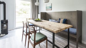 A modern kitchen with a wooden table, chairs, and a built-in bench with cushions. - Fischer Heiligenhafen 4d (Heiligenhafen)