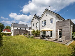 A two-story house with a patio area, a small deck, and a lawn. - Fischer Heiligenhafen 4d (Heiligenhafen)