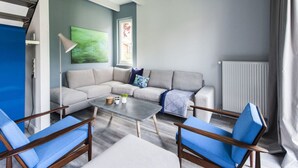 A modern living room with a sectional sofa, two blue armchairs, a coffee table, and a large abstract painting on the wall. - Fischer Heiligenhafen 4d (Heiligenhafen)